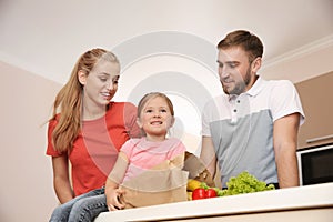 Happy young family with healthy food in paper bag