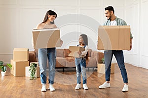 Happy young family holding boxes in new flat