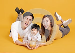 Happy young family holding piggy bank