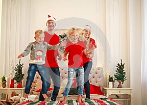 Happy young family jumping and fun at home in bed at Christmas decorations