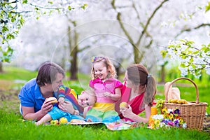 Happy young family with kids having picnic outdoors