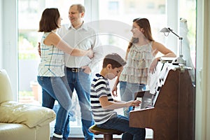 Happy young family listening how cildren plays piano music