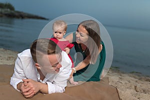 Happy young family with little child, having fun on the beach