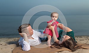 Happy young family with little child, having fun on the beach.