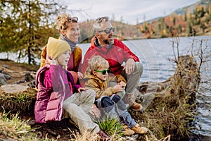 Happy young family with little children, resting near lake in mountains.