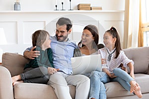 Happy family rest on sofa using modern laptop