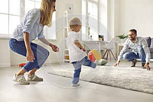 Happy young family with little son playing ball and having fun together