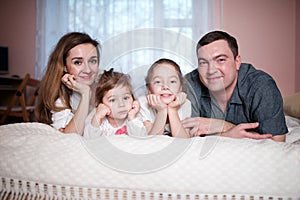 Happy young family lying in bed