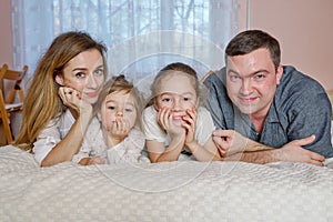 Happy young family lying in bed