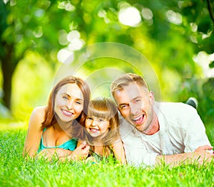 Happy young family lying on green grass