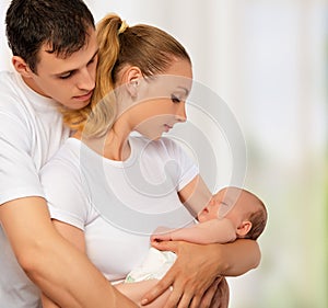 Happy young family of mother, father and newborn baby in their a