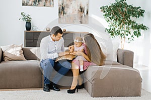 Happy young family with one year old girl playing in the living room of their new home