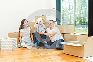 Happy young family, parents daughter and son, unpacking boxes and moving into a new home. funny kids run in with boxes