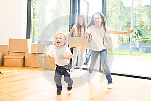 Happy young family, parents daughter and son, unpacking boxes and moving into a new home. funny kids run in with boxes