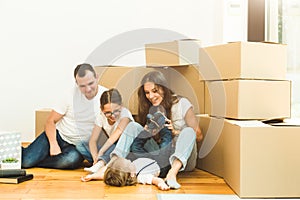 Happy young family, parents daughter and son, unpacking boxes and moving into a new home. funny kids run in with boxes