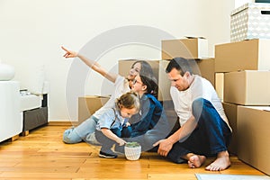 Happy young family, parents daughter and son, unpacking boxes and moving into a new home. funny kids run in with boxes