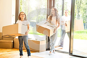 Happy young family, parents daughter and son, unpacking boxes and moving into a new home. funny kids run in with boxes