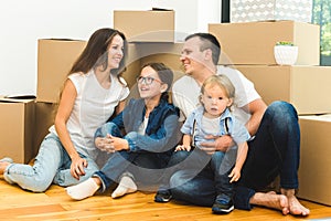 Happy young family, parents daughter and son, unpacking boxes and moving into a new home. funny kids run in with boxes