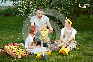 The happy young family during picking apples in a garden outdoors