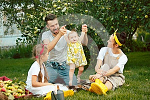 The happy young family during picking apples in a garden outdoors