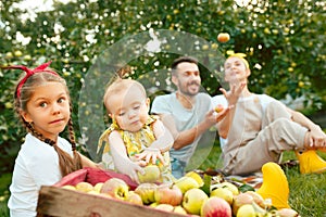 The happy young family during picking apples in a garden outdoors