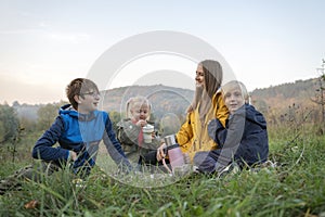 Happy young family on picnic communicate and smiling. Three siblings with mother resting on the nature