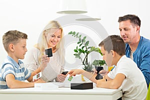 Happy young family playing card game at dining table at bright modern home.