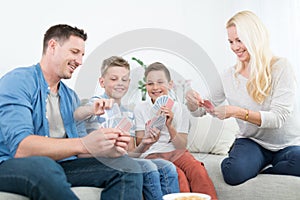 Happy young family playing card game at home.