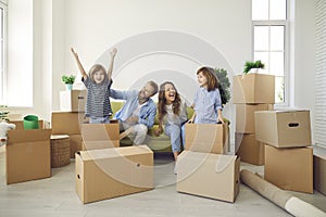 Happy young family playing with cardboard boxes and having fun in their new home