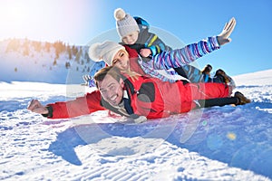 Happy young family playing in fresh snow at beautiful sunny winter day outdoor in nature