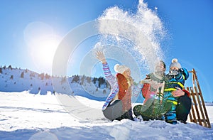 Happy young family playing in fresh snow at beautiful sunny winter day outdoor in nature