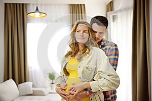 Happy young family pregnant expecting a baby dancing at home