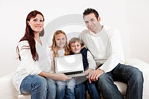 Happy young family presenting laptop