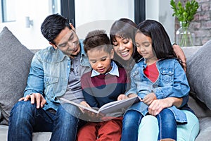 Happy young family reading a book together