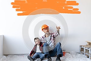 Happy young family is renovating their house, father is holding son sit on the floor. White moaning with space for text.