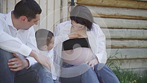 A happy young family is resting in the park. A wife with her husband and child relaxing in nature