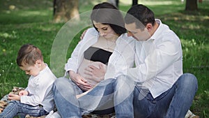 A happy young family is resting in the park. A wife with her husband and child relaxing in nature