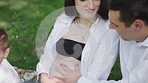 A happy young family is resting in the park. A wife with her husband and child relaxing in nature