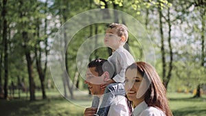 A happy young family is resting in the park. A wife with her husband and child relaxing in nature