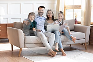 Happy young family sit on couch using modern laptop