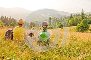 Happy young family sitting back view mountain family nature vacation green travel together nature child mountain kid