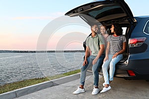 Happy young family sitting in car trunk