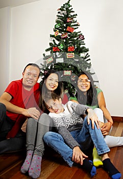 Happy young family sitting by Christmas tree