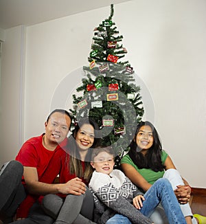 Happy young family sitting by Christmas tree