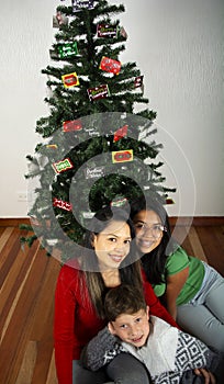 Happy young family sitting by Christmas tree