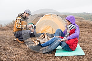 Happy young family sitting near tent