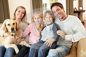 Feliz joven familia sobre el sofá posesión el perro 