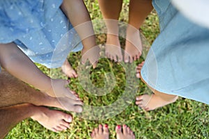 Happy young family spending time outdoor on a summer day. Feet on the grass