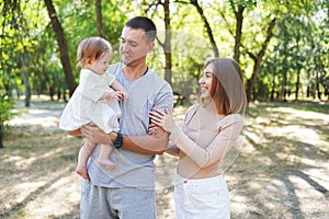 Happy young family spending time together, mother and father with baby outside in green nature