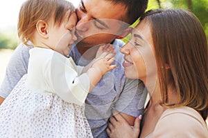 Happy young family spending time together, mother and father with baby outside in green nature